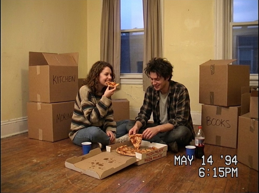 A couple eating pizza among moving boxes